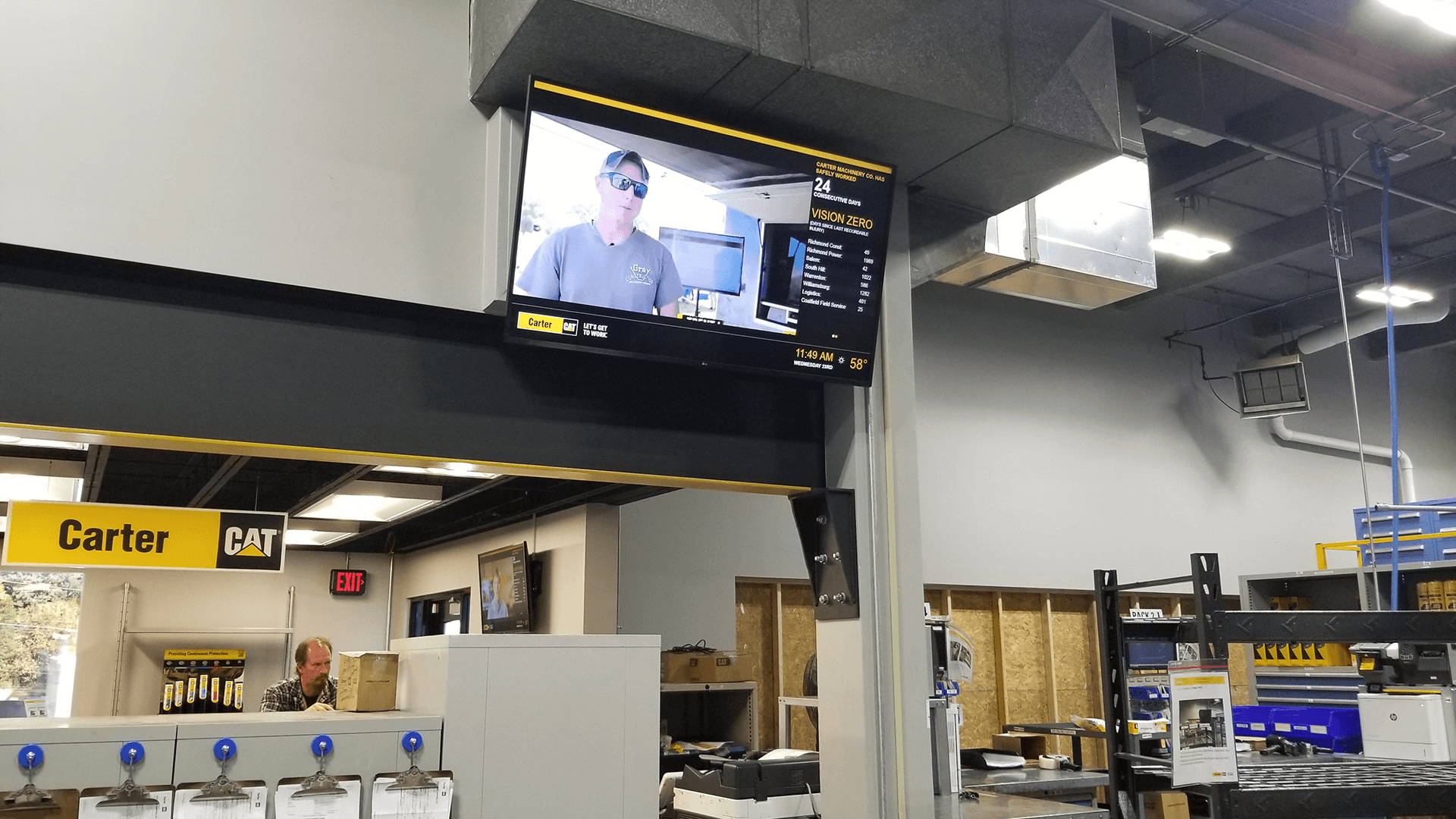 Black and yellow digital signage featuring production metrics within a warehouse