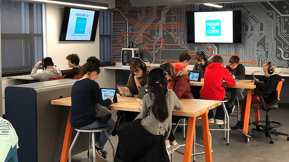 A classroom with students engaging on tablets with headphones.