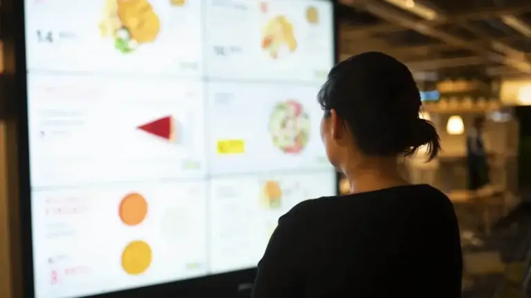 Digital signage menu board viewed by woman, Reach Media Network
