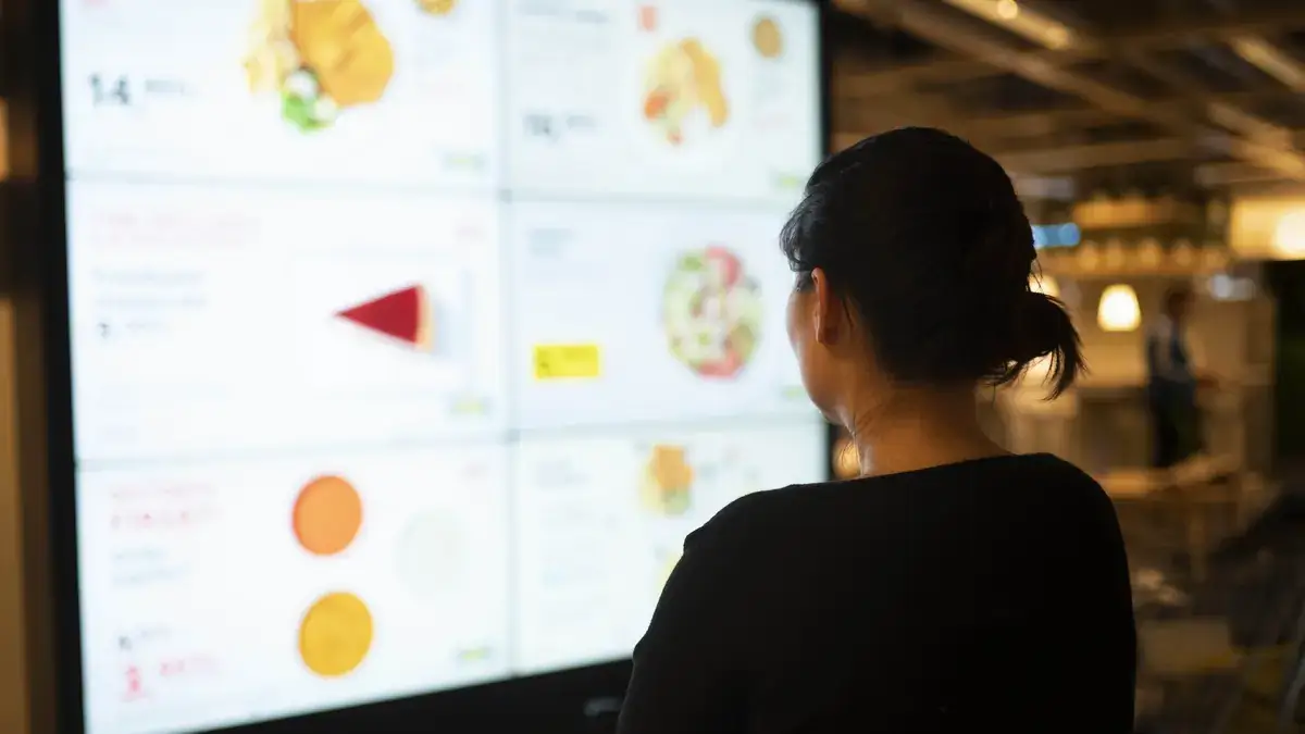 Digital signage menu board viewed by woman, Reach Media Network