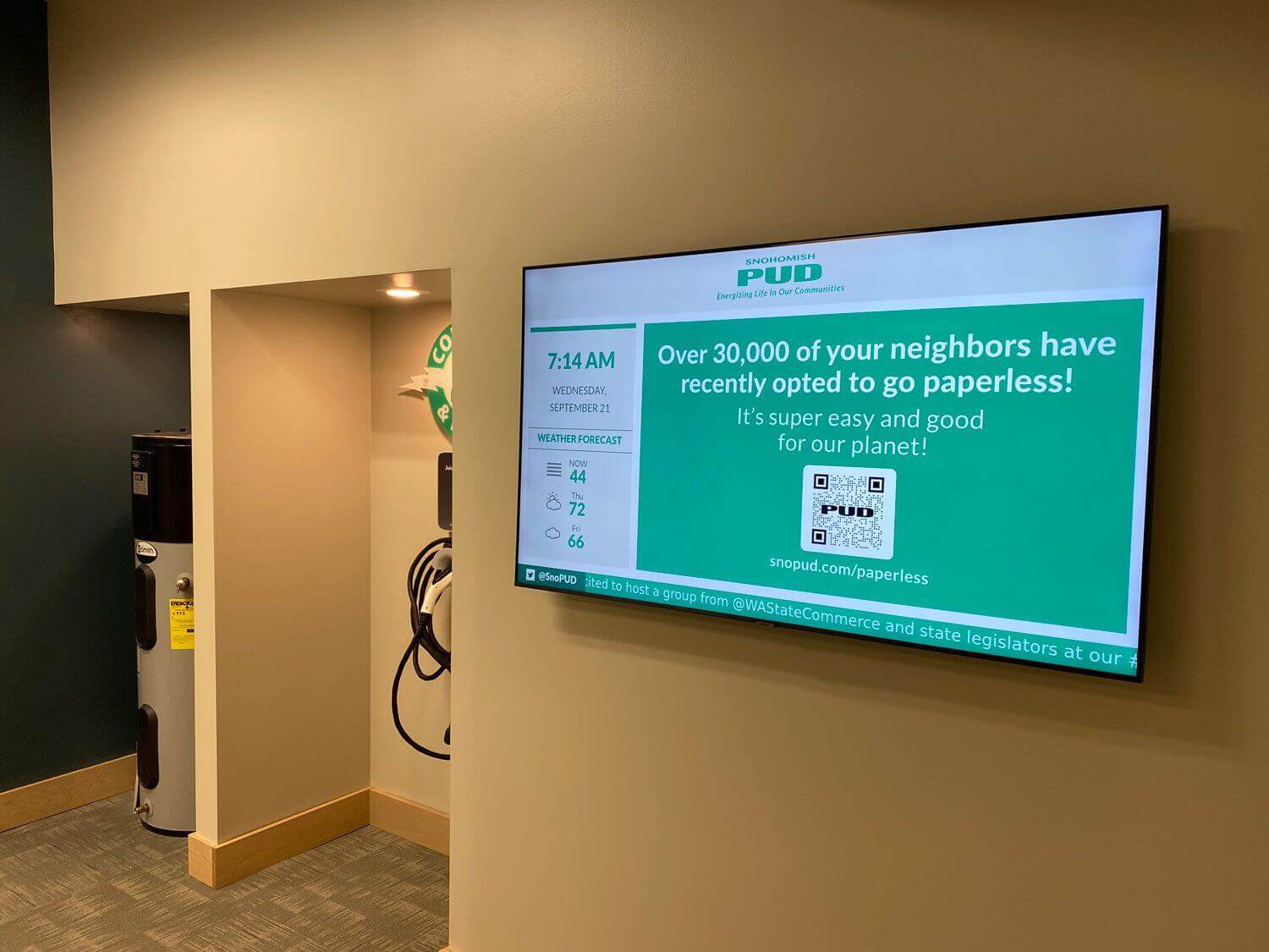 pic-1 Snohomish county public utilities department screen featured next to electric car charger, displaying promotion for going paperless.