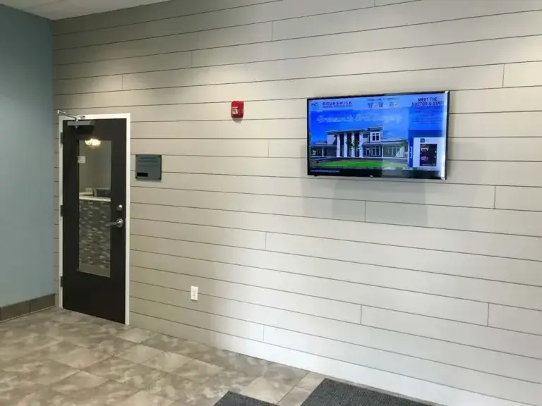 Brunswick Dental Specialists digital signage screen from Reach Media Network featured by lobby entrance, displaying welcome message and staff spotlight.