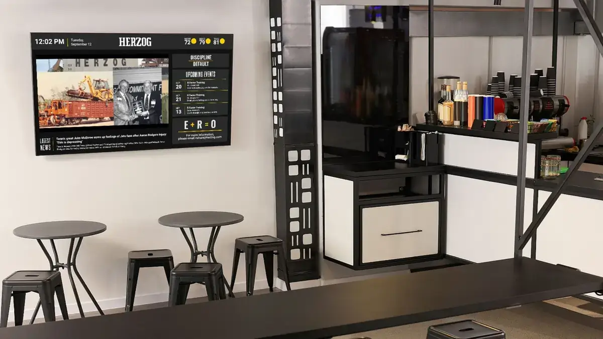 Herzog break room digital signage from Reach Media Network displaying upcoming events, latest news, and historical imagery.