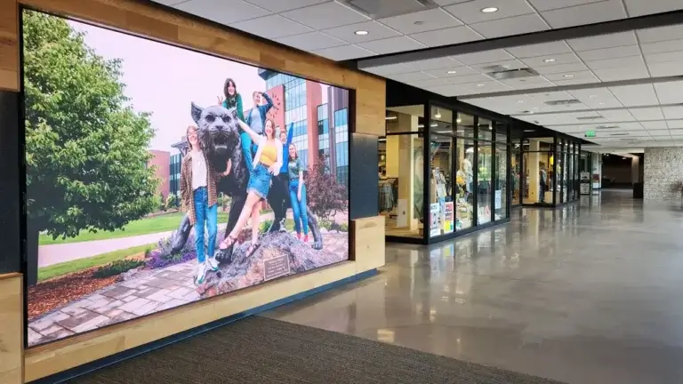 Large school digital signage from Reach Media Network featured in Northern Michigan University hallway, next to student store.