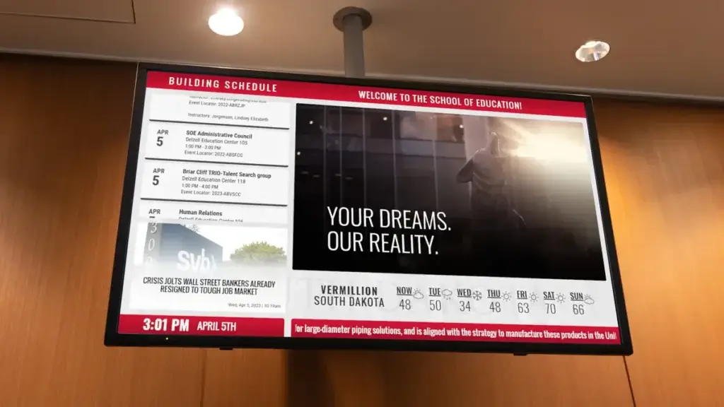 University of South Dakota School of Education digital signage example from Reach Media Network displaying scrolling calendar, news headlines, and playlist announcements